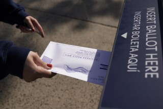 A woman deposits her ballot in an election drop box in Jersey City, N.J., Thursday, Oct. 15, 2020. (AP Photo/Seth Wenig)